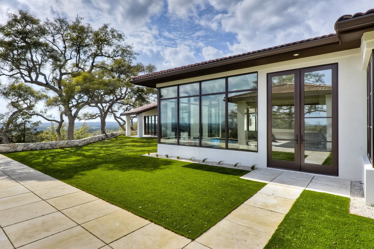Artificial grass installation at a Texas Hill Country luxury home with panoramic views and stone retaining wall